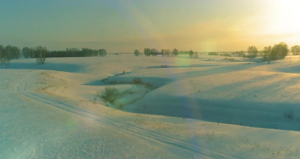 Aerial View of Cold Arctic Field Landscape Trees with Frost Snow Ice River and Sun Rays Over Horizon