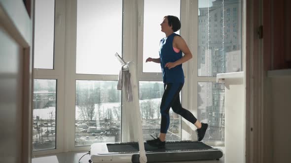 Woman is running on treadmill at home in balcony.