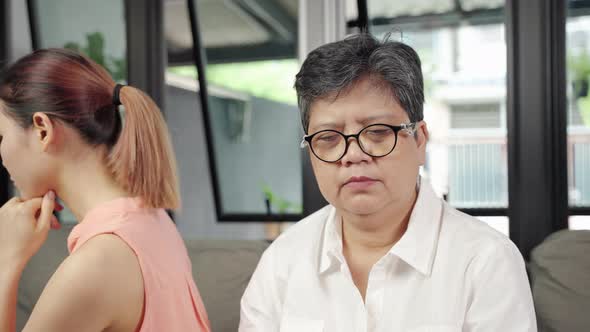 elderly mother and her daughter are sitting with their backs facing each other