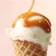 melted caramel sauce flowing on vanilla ice cream scoop in waffle cone close up on beige background - VideoHive Item for Sale
