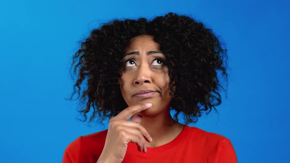 Thinking Mixed Race Woman Looking Up and Around on Blue Studio Background