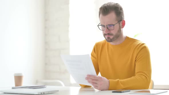 Man Upset While Reading Documents in Office