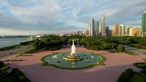 Beautiful Fountain In City Park With Downtown City Skyline At Sunrise Drone