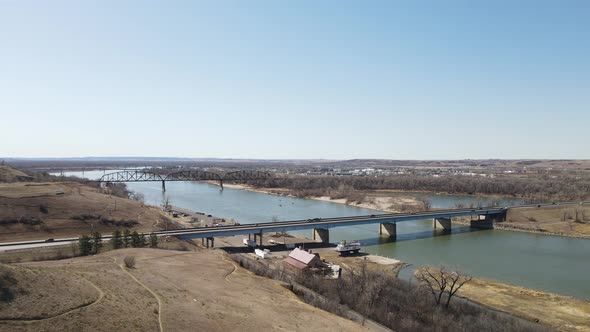 View over river with bridges in autumn blue sky. Rolling hills for hiking nearby. Ship yard on shore alt