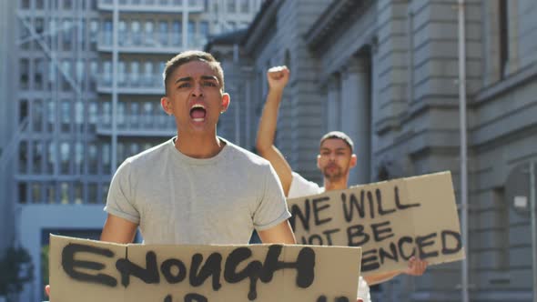 Two mixed race men on a protest march holding placards raising hands and shouting