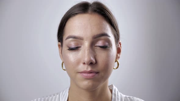 Portrait of Gorgeous Caucasian Woman with Dark Hair Tied in Bun Looking at Camera with Beautiful