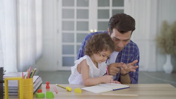Young father teaching his cute little daughters' study. Children education, home schooling concept