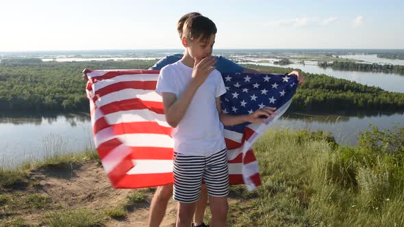 Blonde Boy Waving National USA Flag Outdoors Over Blue Sky at the River Bank