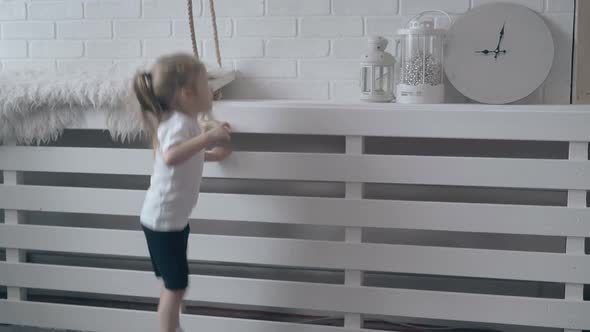 Little Girl with Ponytail Jumps on Wooden Brown Floor