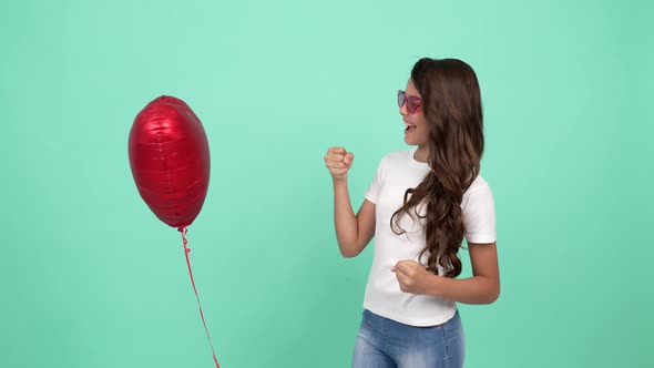 Smiling Child in Sunglasses Having Fun with Heart Party Balloon Boxing and Punching Fun