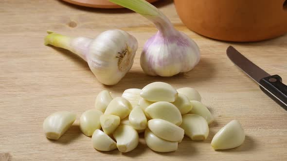 Heap of raw peeled garlic with fresh picked garlic in the background 