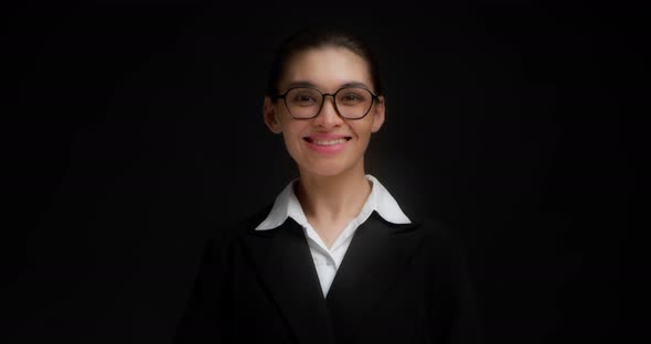 Asian Business Woman in Glasses and Formal Clothes Stands and Looks at Camera