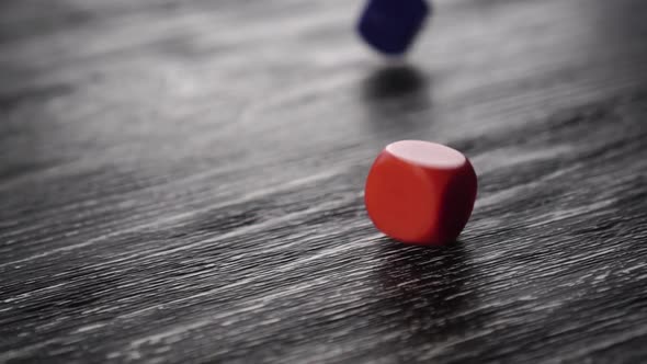 Three multi-colored game dice fall on a black old wooden table