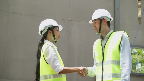 Asian structure engineer and construction worker making handshake on building working site workplace