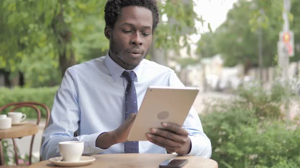 African Businessman Using Tablet Sitting in Outdoor Cafe