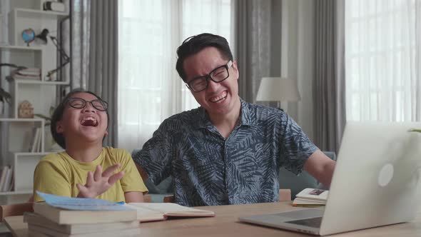 Happy Asian Father And His Daughter Looking At Laptop Computer In Living Room