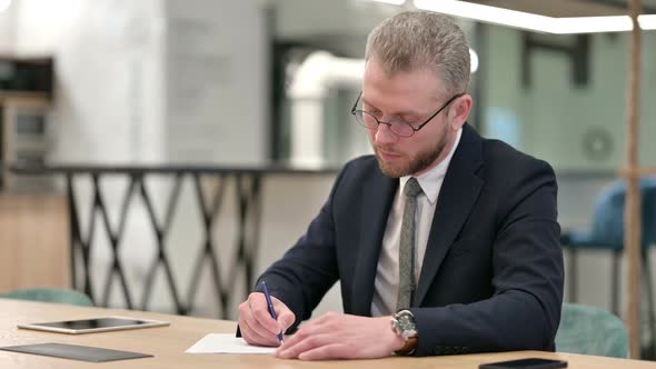 Serious Young Businessman Doing Paperwork in Office