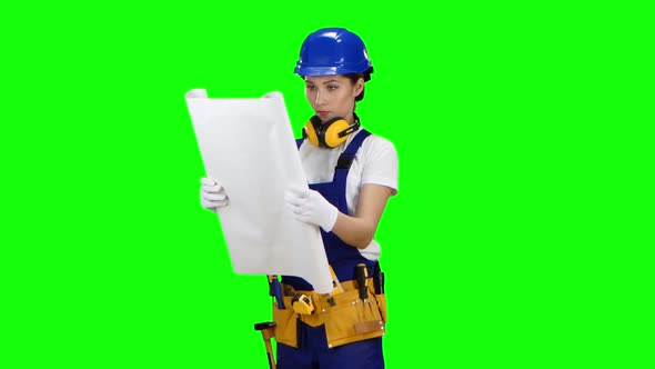 Girl in a Helmet and a Drawing in Her Hands Is Standing, Green Screen