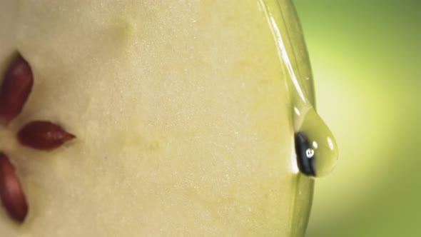 Drop of Water Flows Down the Surface of a Ripe Juicy Green Apple Slice