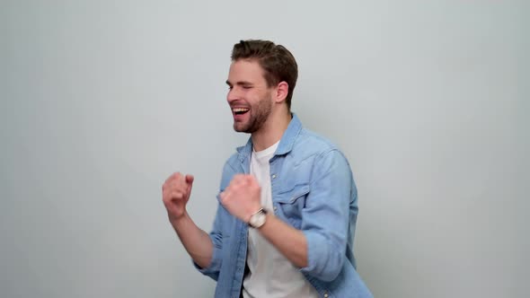 smiling young caucasian man showing win yes gesture