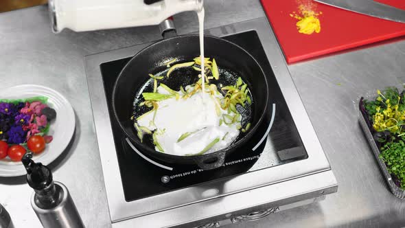 The Chef Pours Cream Into a Saucepan While Cooking Italian Pasta