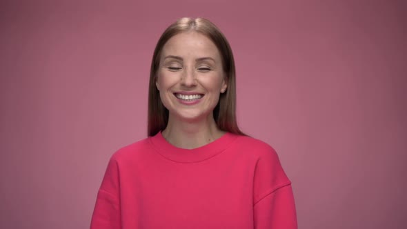 Attractive pleasant caucasian girl wearing pink sweater looking into the camera and turning around