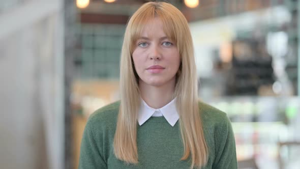 Portrait of Serious Young Woman Looking at the Camera in Cafe