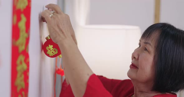 Asian Senior Woman Decorate Her House For Chinese New Year Celebrations.