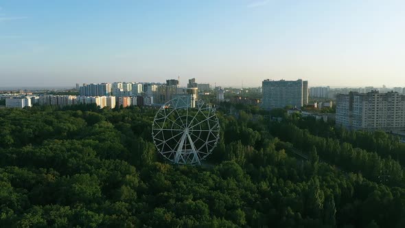 Ferris Wheel Carousel in the City, Aerial View. Huge Ferris Wheel Is Spinning, People Are Sitting in