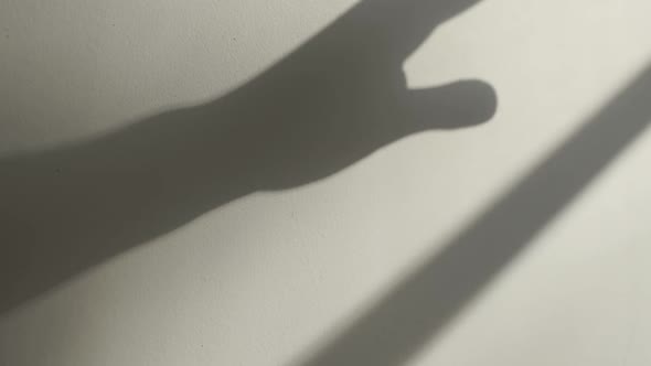 Shadow of a hand on a wall moving around in slow motion