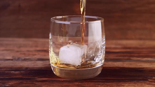 Close Up of Ice Falling and Pouring Whiskey in Glass