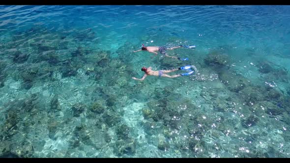 Two lovers tan on tropical bay beach break by shallow sea with white sandy background of the Maldive