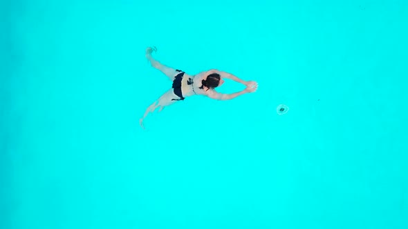 View From the Top As a Woman in a Black Swimsuit Swims in the Pool