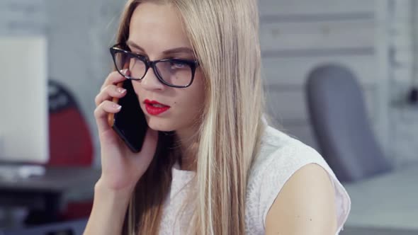 Busy Young Girl Speaking on Cellular in Office