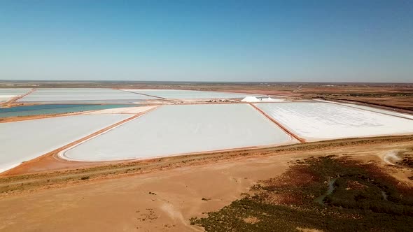 Aerial footage of expansive solar evaporation salt mining fields, slide pan wide shot