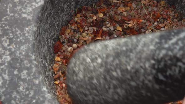 Super Closeup of a Pestle Grinding and Mixing Various Kinds of Spices