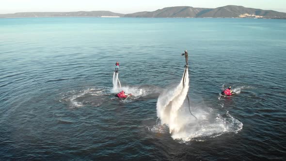Sportive Men Doing Tricks with Jet Packs Over Sea Water
