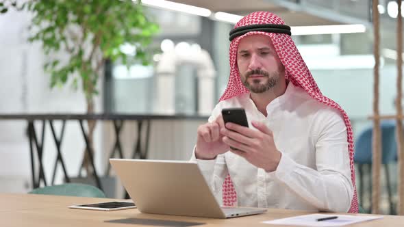 Professional Arab Businessman Using Smartphone and Laptop 