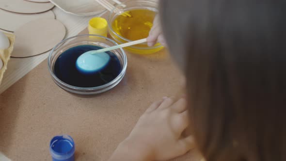 Girl Dipping Easter Egg in Blue Food Coloring