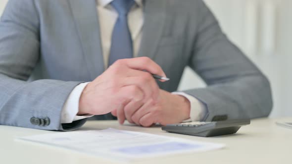 Close Up of Businessman Making Calculations Writing on Paper