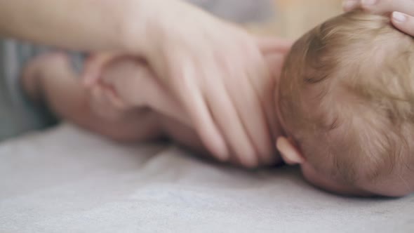 Infant Boy with Short Hair Lies on Stomach on Changing Table