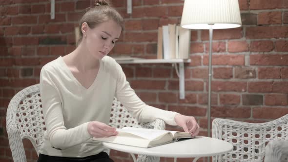 Young Woman Reading Book in Modern Office