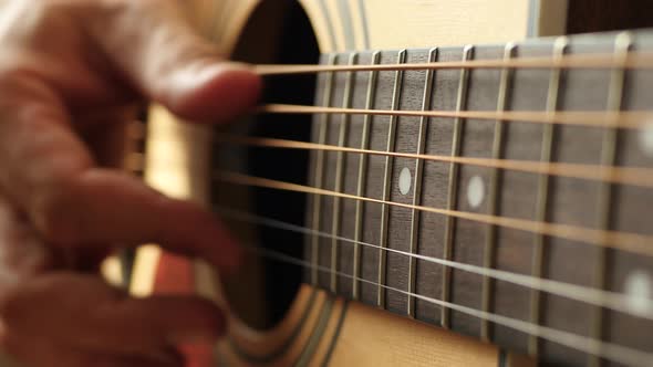 The Musician Plays the Yellow Acoustic Guitar, Touching the String with His Finger