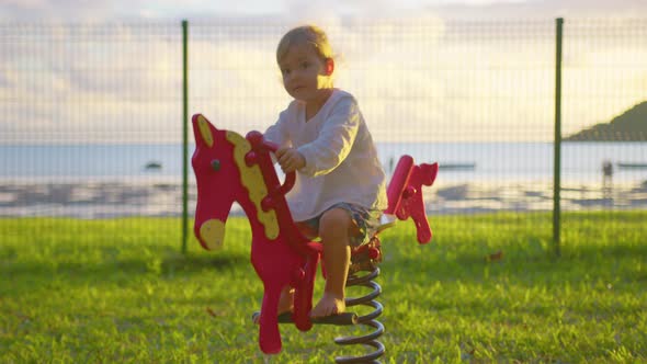 Baby Rides on a Horse Swing on the Playground