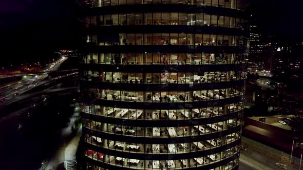 Aerial view boom down of an office building with people working late at night, Titanium Park, Santia