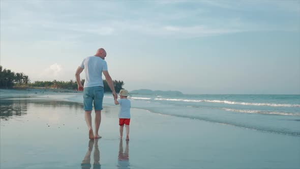 Silhouetted Happy Father and Son Playing and Having Fun on the Beach at Sunset