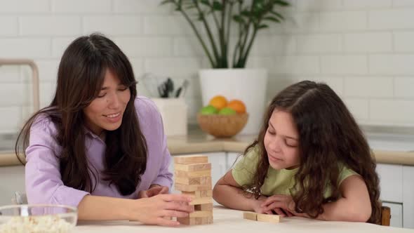 Joyful Mother and Cheerful Daughter are Playing a Board Game at Home at the Table Removing Wooden