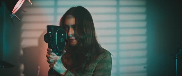 An actress is holding a vintage movie camera