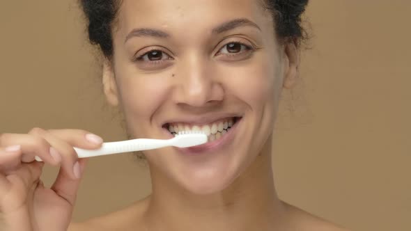 Beauty Portrait of Young African American Woman is Brushing Her Teeth with Toothbrush