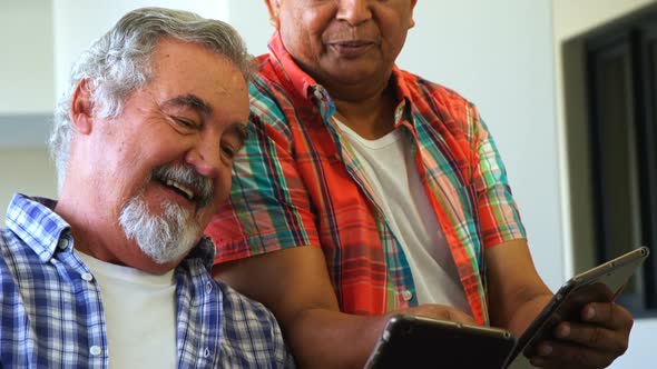 Happy senior friends using digital tablet on sofa